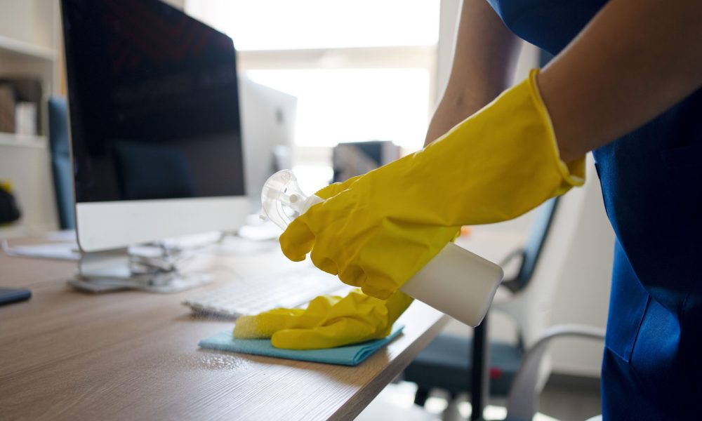 Désinfection d'un bureau avec un spray nettoyant et un chiffon.