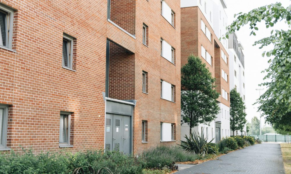 Façade d'immeubles résidentiels en briques rouges avec un espace piétonnier.
