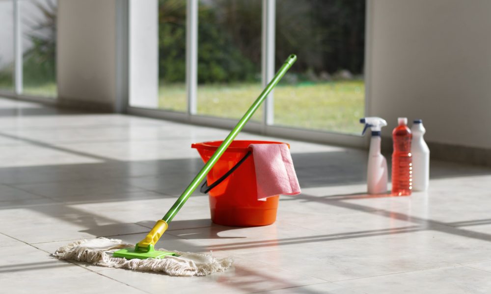 Seau, serpillière et produits de nettoyage pour laver un sol carrelé.