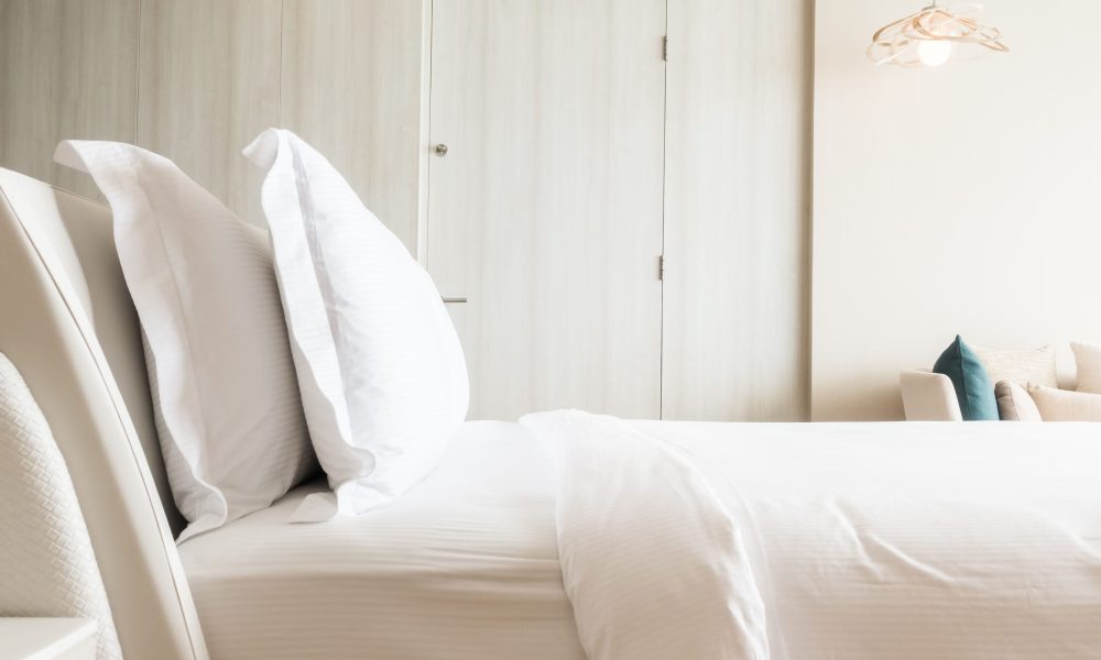 Lit soigneusement fait dans une chambre lumineuse avec des draps blancs.